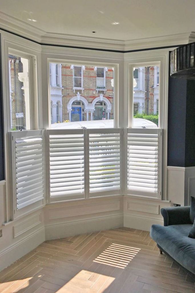 This bow window is styled with blinds that cover only the lower part of it to let light inside.