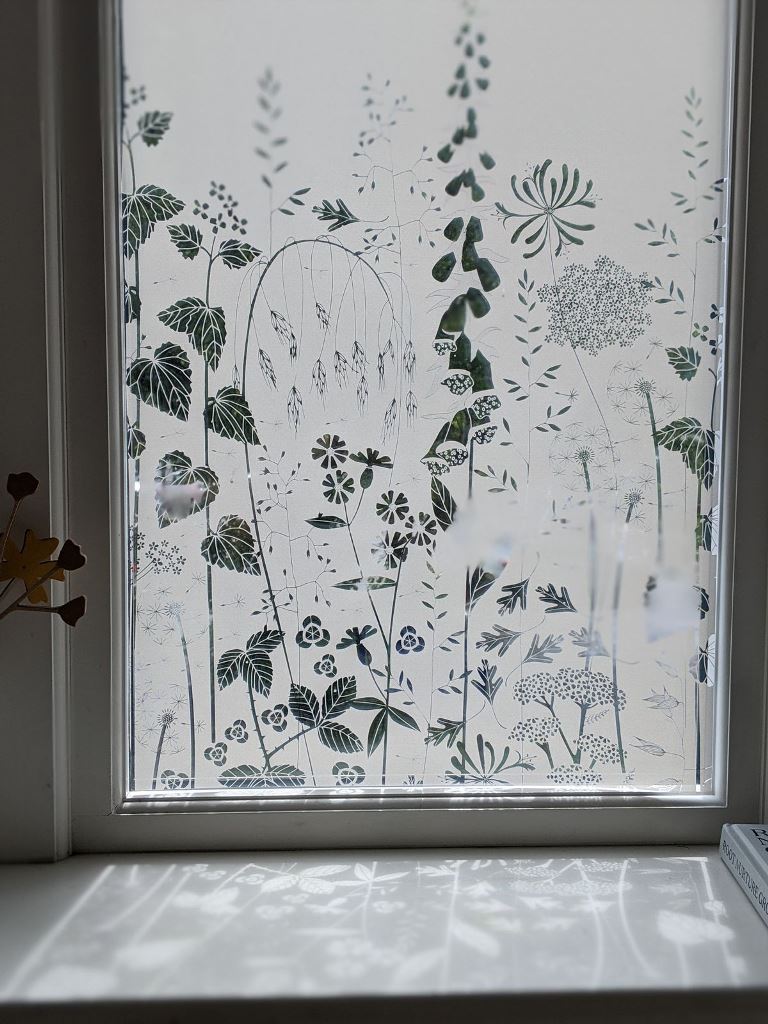 The window is styled with botanical film that not only blocks out the view but also adds beauty to the space.