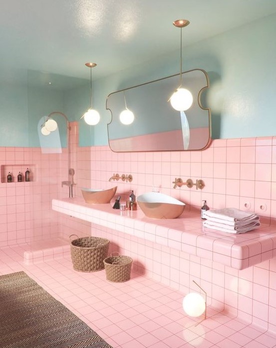 Bright pink tiles paired with light blues, with gold fixtures and black grout for a bold look.