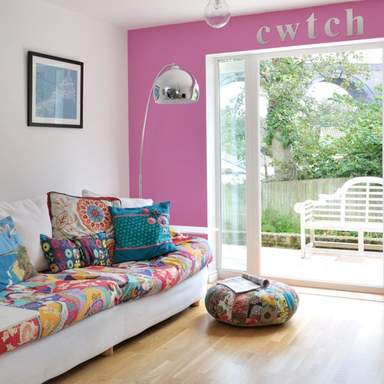 A hot pink wall, bright printed pillows and upholstery make the living room feel and look bright and summer-like.