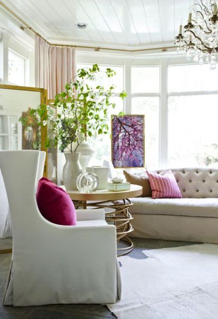 Greenery branches, a floral artwork and bright pillows for infusing a neutral living room with color, prints and bring a summer feel.