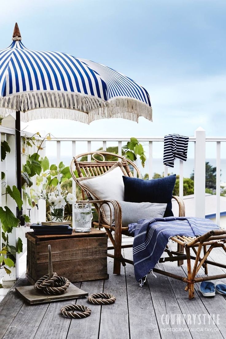 A nautical terrace with a rattan lounger and a wooden chest, an umbrella, some nautical textiles and greenery to refresh the space.