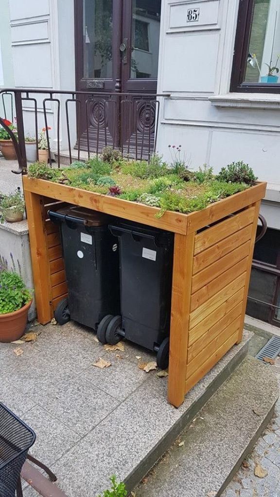 The cover is made of stained wood, with a tray with greenery and succulents on top.
