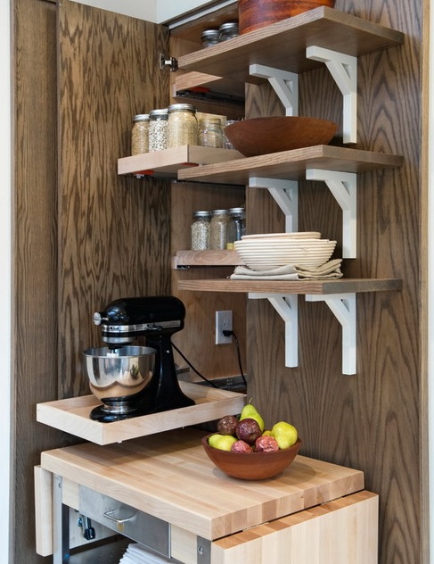 A narrow mini cabinet with a retractable shelf that hides a mixer and spices over it on matching shelves.