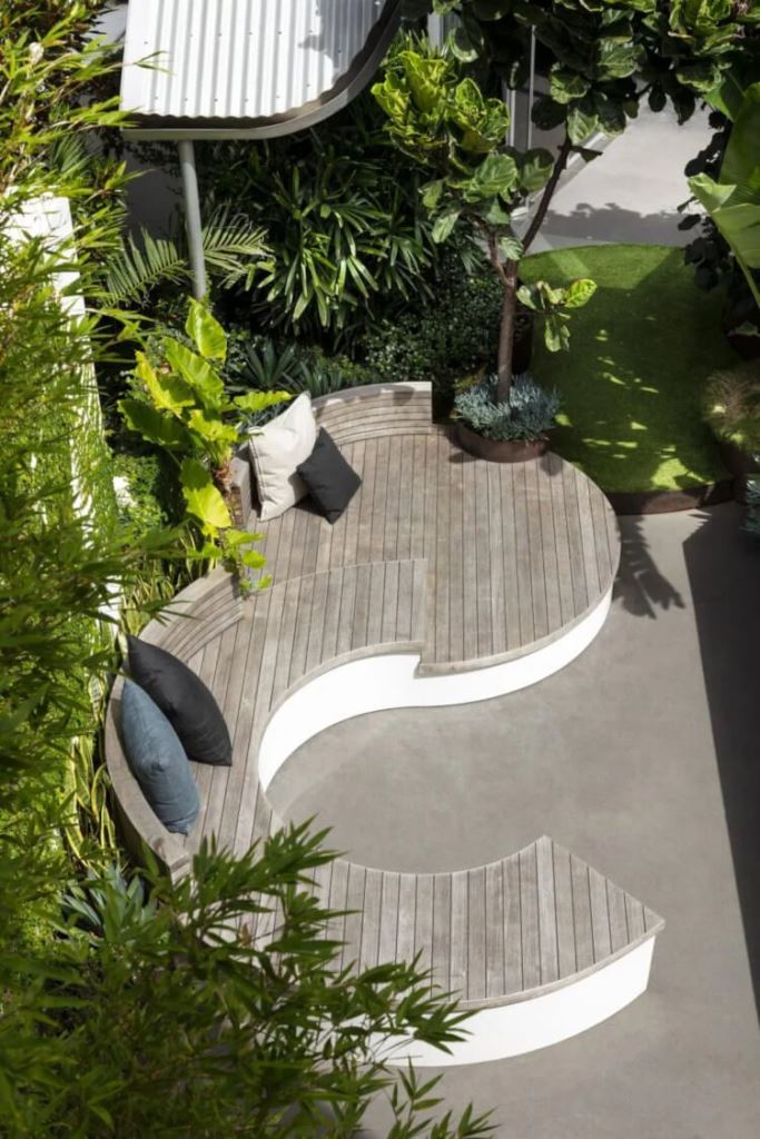 This large curved bench covered with reclaimed wood is a cool solution for a modern patio.