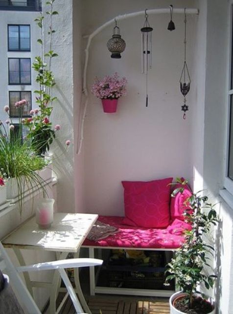 A small summer balcony in white, with bright pink and fuchsia touches, potted blooms and greenery and boho candle lanterns.