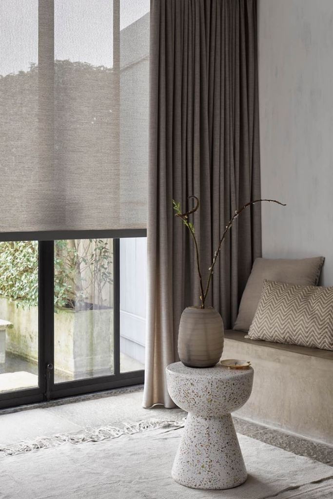 The contemporary space features elegant semi-sheer shades and classic drapes to block out any views.