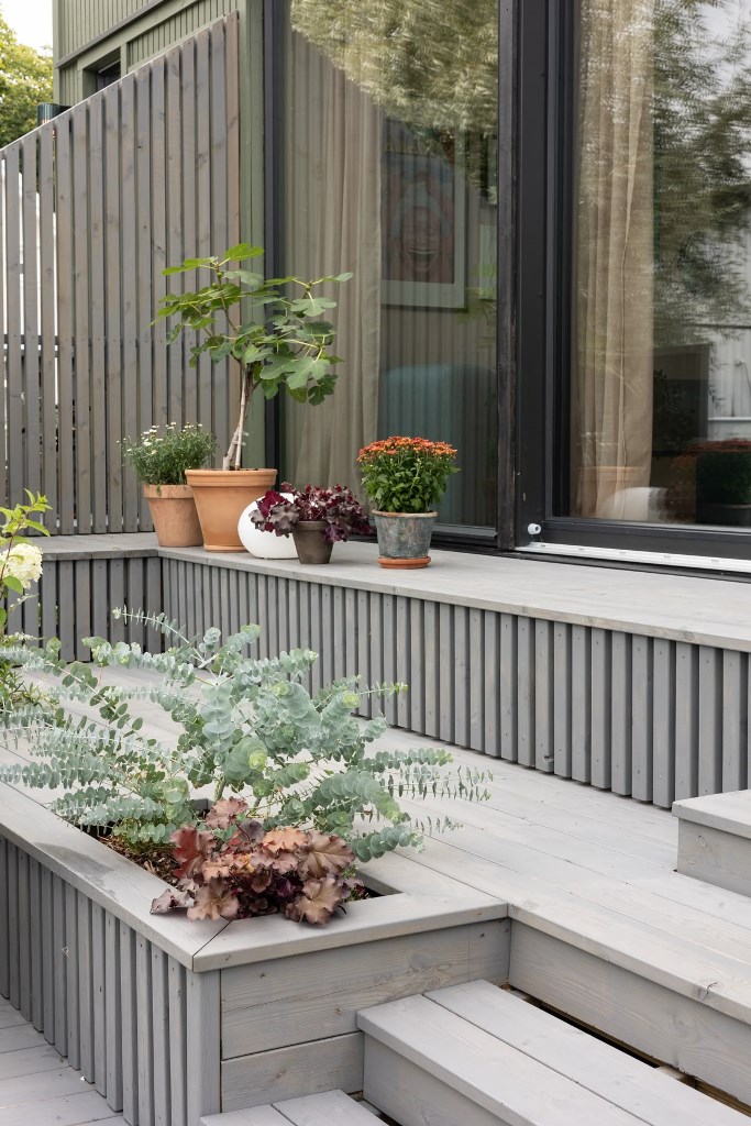 This beautiful front space is done with grey-colored wood: there are steps and built-in planters that create a serene look.