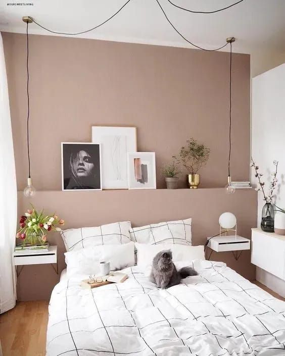 This small Scandinavian space is done with a mauve accent wall with a built-in headboard, wall-mounted nightstands and decor.