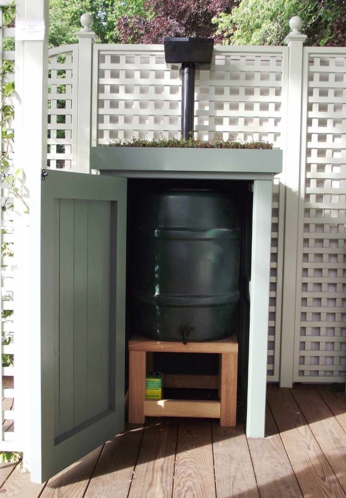 The barrel is hidden inside a cabinet, which is topped with some greenery.
