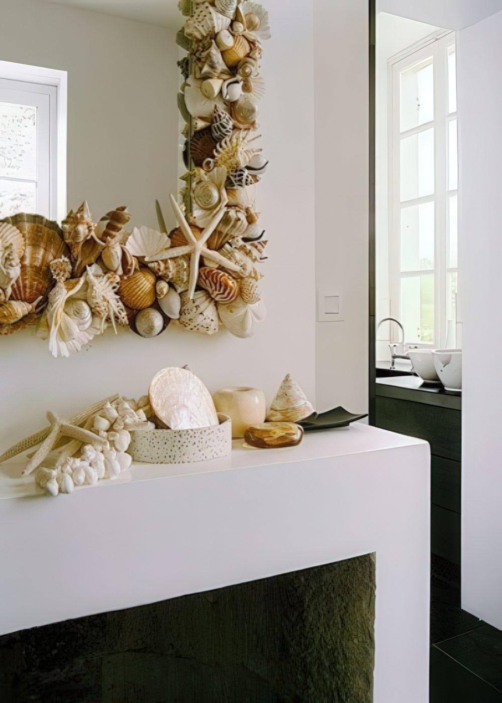 seashells and starfish on the mantel and covering the mirror frame make the space feel coastal and sea-inspired at the same time.