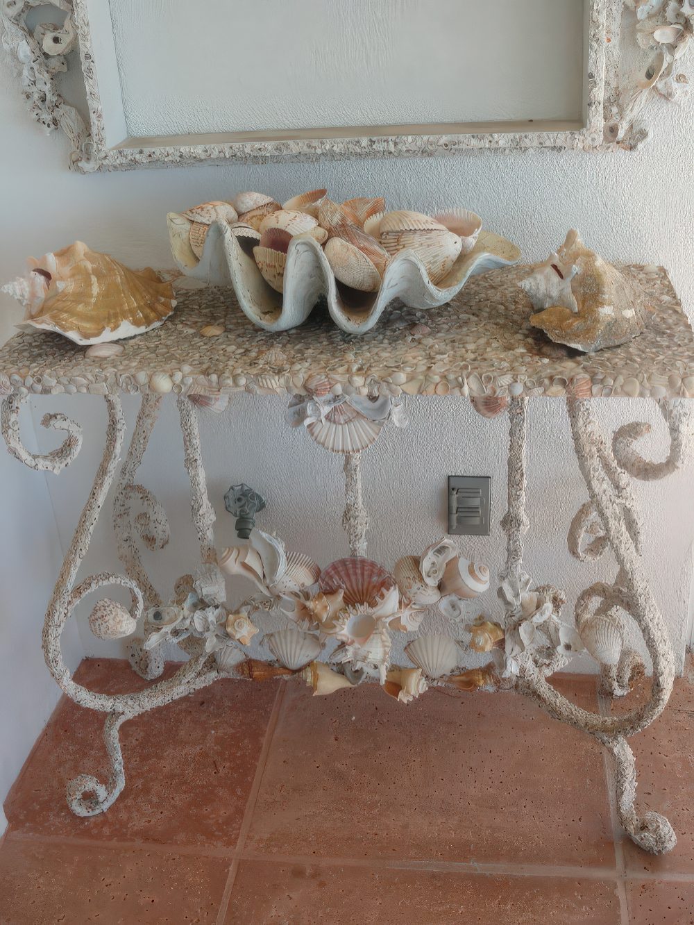 A vintage and elegant console table with seashells - decorated with them and with seashells on it for a coastal feel.