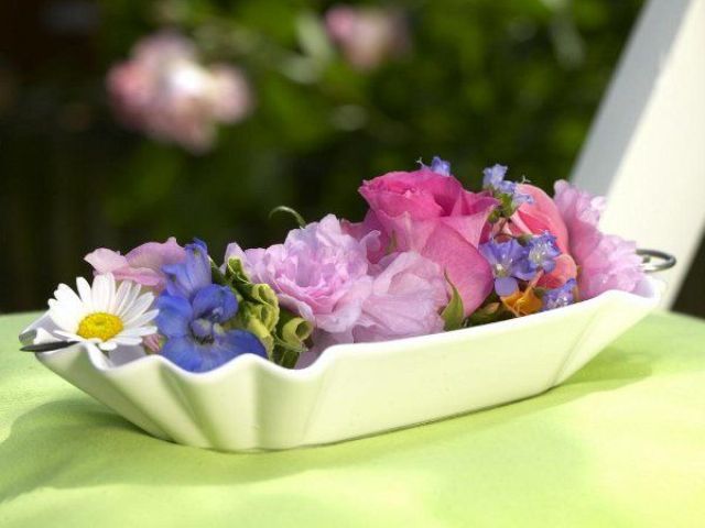 A white bowl with some colorful flower heads is a cool bright centerpiece or decoration for a vintage space.