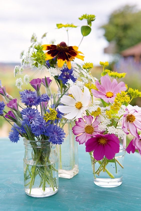 Jars and glasses with bright blooms and white ones will compose a cool summer centerpiece.