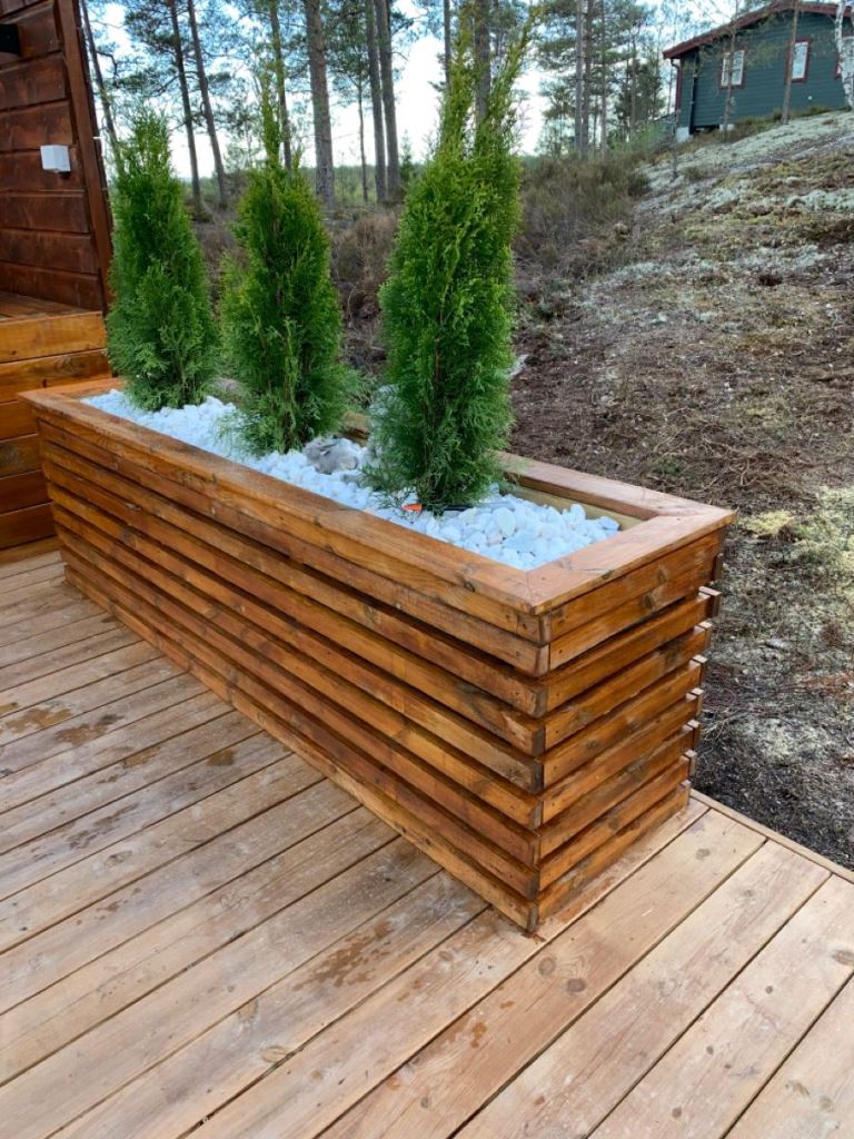 This large stained planter is used to grow trees, and they mark the edge of the deck.