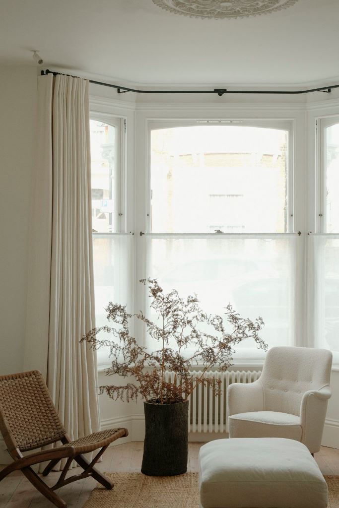 The bow window is done with semi-sheer shades and neutral curtains to keep privacy and not only.