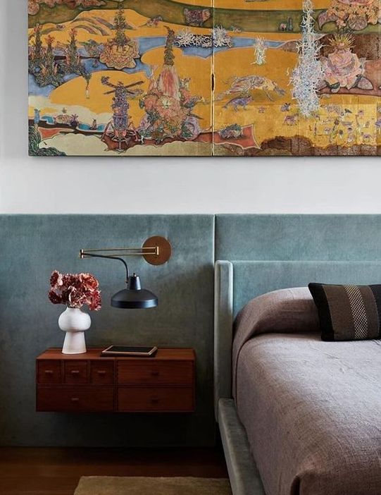 The bedroom is done with an aqua upholstered bed and a matching paneled headboard, floating nightstands and a bold artwork.