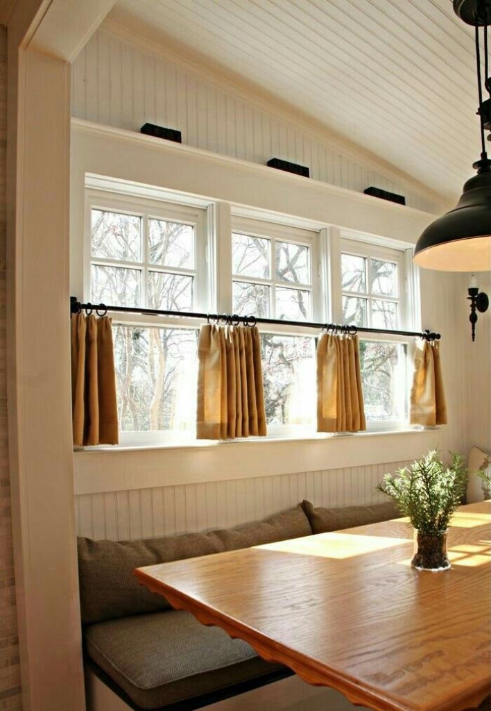 The farmhouse dining space is finished off with mustard cafe curtains that match the colors and add a cozy feel to the nook.