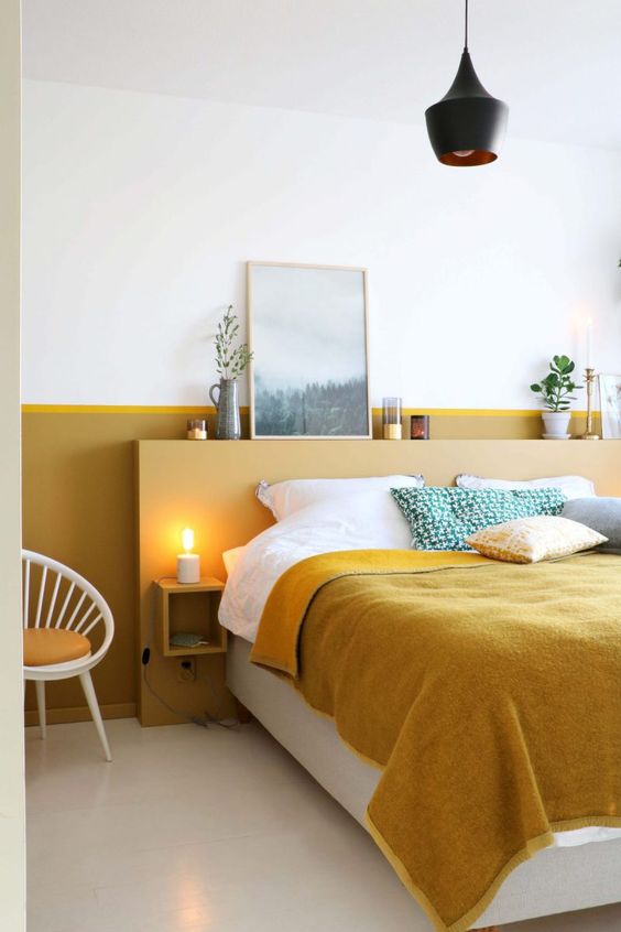 The modern bedroom is done with a mustard color block wall and a matching headboard with nightstands and decor.