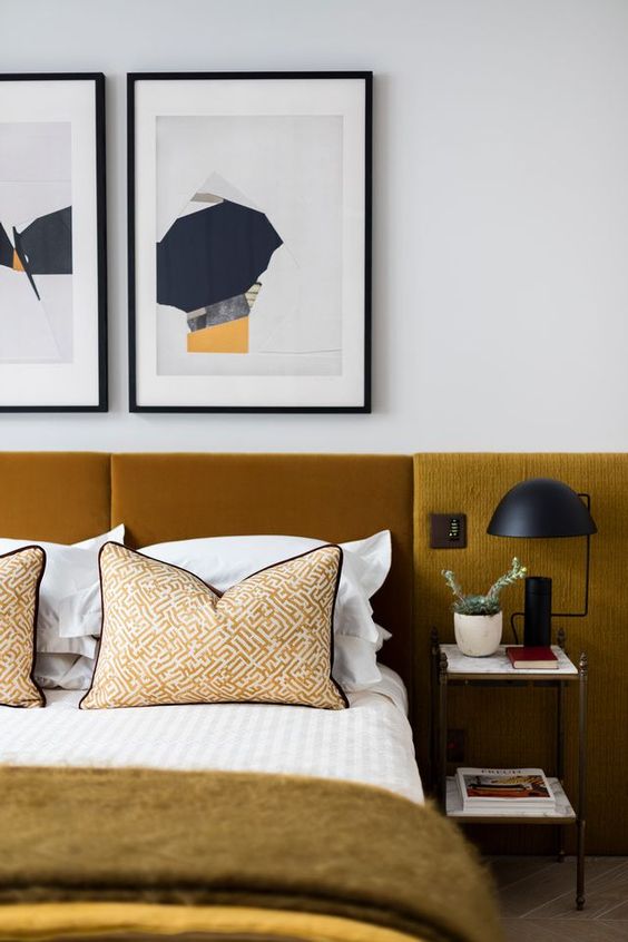 The refined sleeping space is done with upholstered mustard panels that are an extended headboard, and black accents for drama.