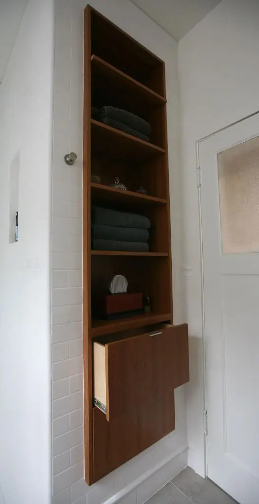 This stained niche is done with shelves and drawers for storage, and its warm look adds coziness to the white bathroom.