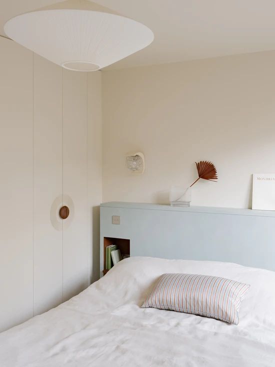 This serene space is done in creamy, with a bed with pale blue storage headboard and decor on top for a soft touch of color.