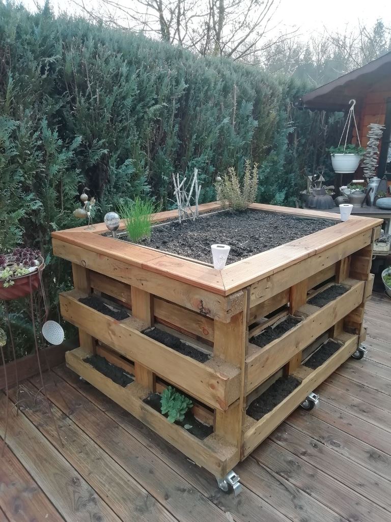 This pallet garden includes a large garden bed on top and smaller ones on the sides, and casters make this construction mobile.