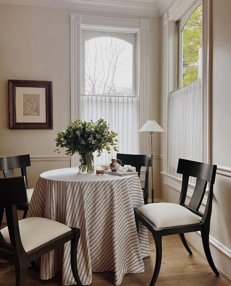 This elegant dining space is styled as a French cafe, and the floor lamp, art and pleated cafe curtains highlight the style.
