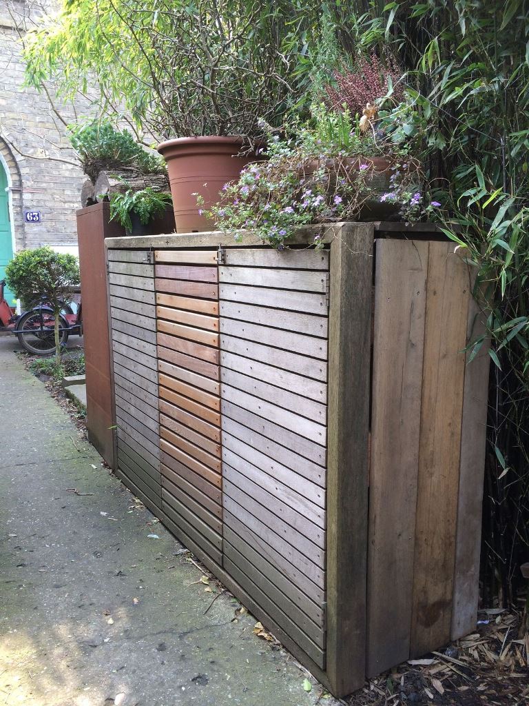 This reclaimed wooden box hides several trash cans and can be DIYed using pallets.
