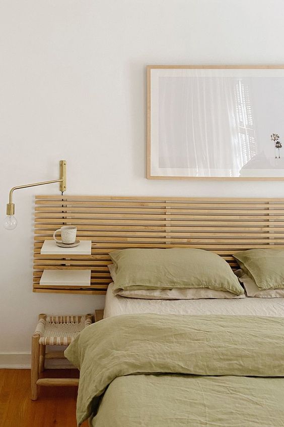 The neutral bedroom is done with a bed and an added ribbed headboard with floating shelves, a woven stool and lovely decor.