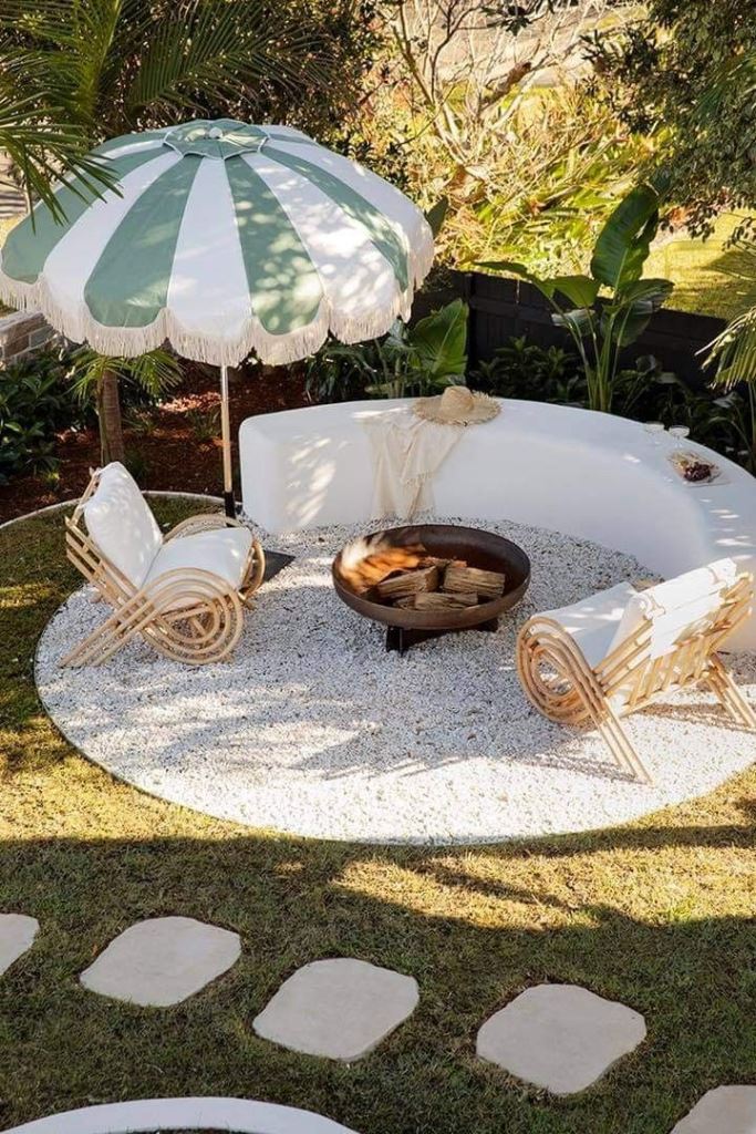 The modern patio is done with gravel, a slab rounded bench, rattan chairs and an umbrella.