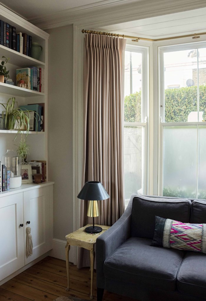 The bow window is done with semi-sheer film and tan curtains to block the views and keep the room more private.