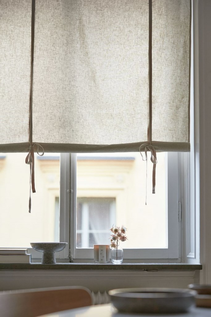 The window is covered with light-colored shades with bows that can easily block out anything.