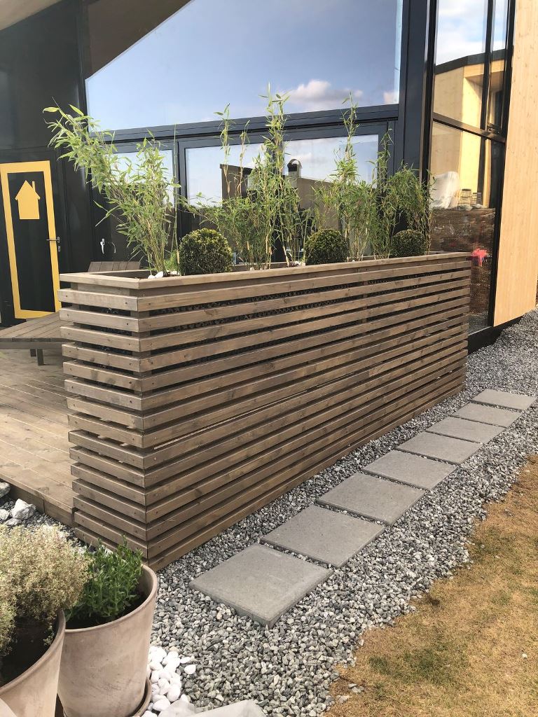 This is a space divider planter built of slats, and you may add storage space inside.