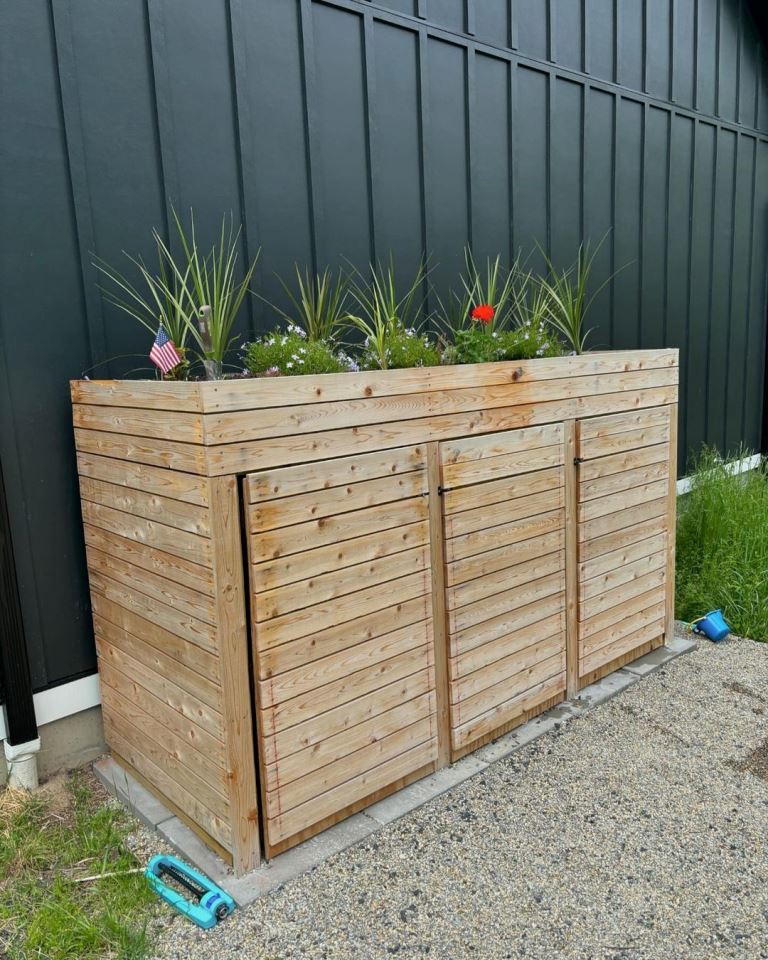 This large stained box hides several trash cans and the tray on top spruces up the look with plants and blooms.