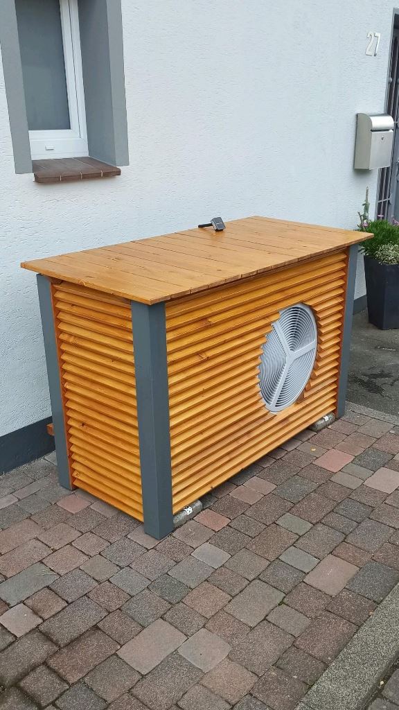 This stained wooden box with a roof keeps the AC unit untouchable until the owners want it.