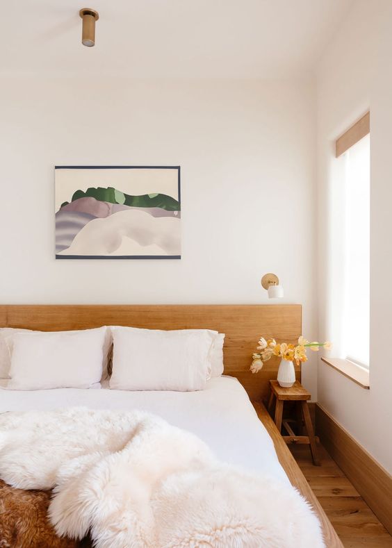 The serene modern bedroom is done with much stained wood, a bed with a matching headboard and a stool.