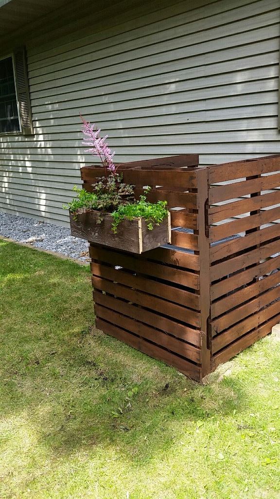 The trash can is hidden with stained screens and a planter attached to them adds a fresh touch.