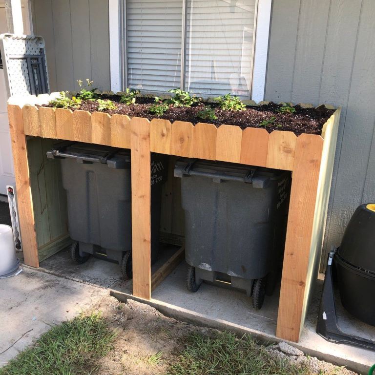 This plywood stand covers a couple of trash cans and the tray on top features some greenery.