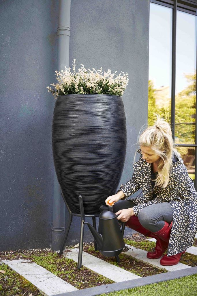 This chic black textural container is topped with flowers and matches the exterior of the house.