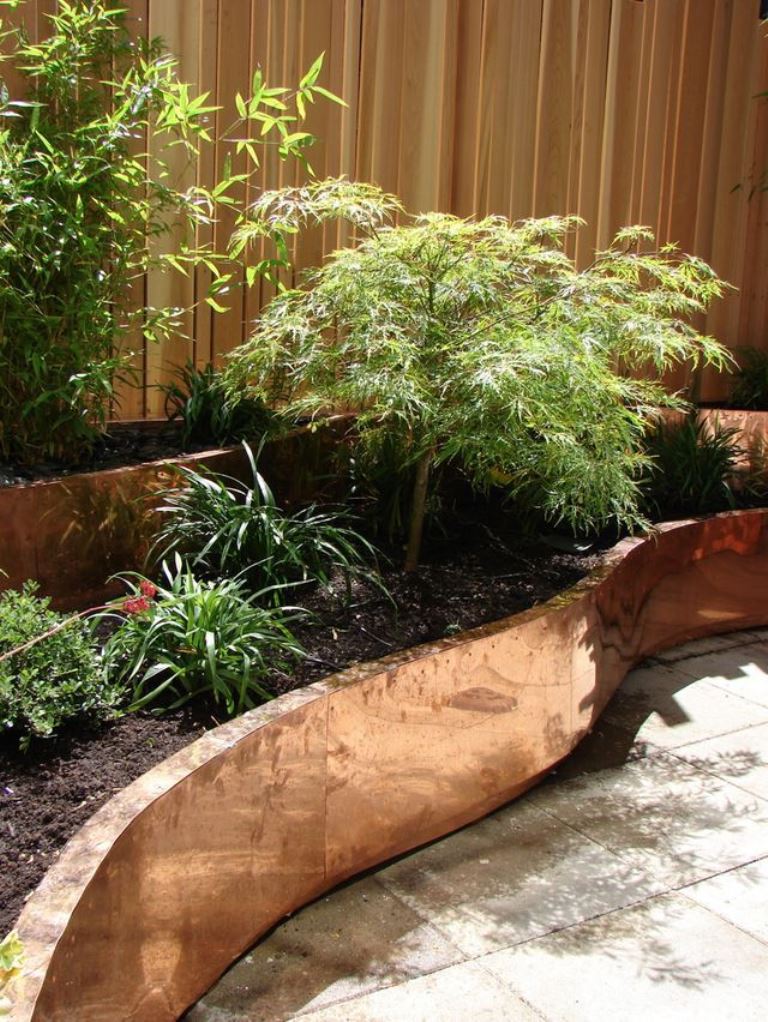 The tiered curved garden bed with greenery is a creative idea for styling a fence or a corner.
