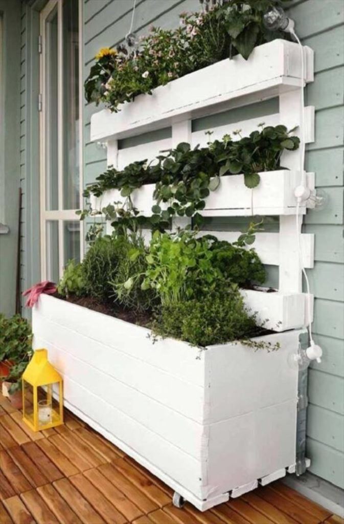 This white mini garden consists of a planter with casters and a vertical part with plant stands, and it's built of a pallet.