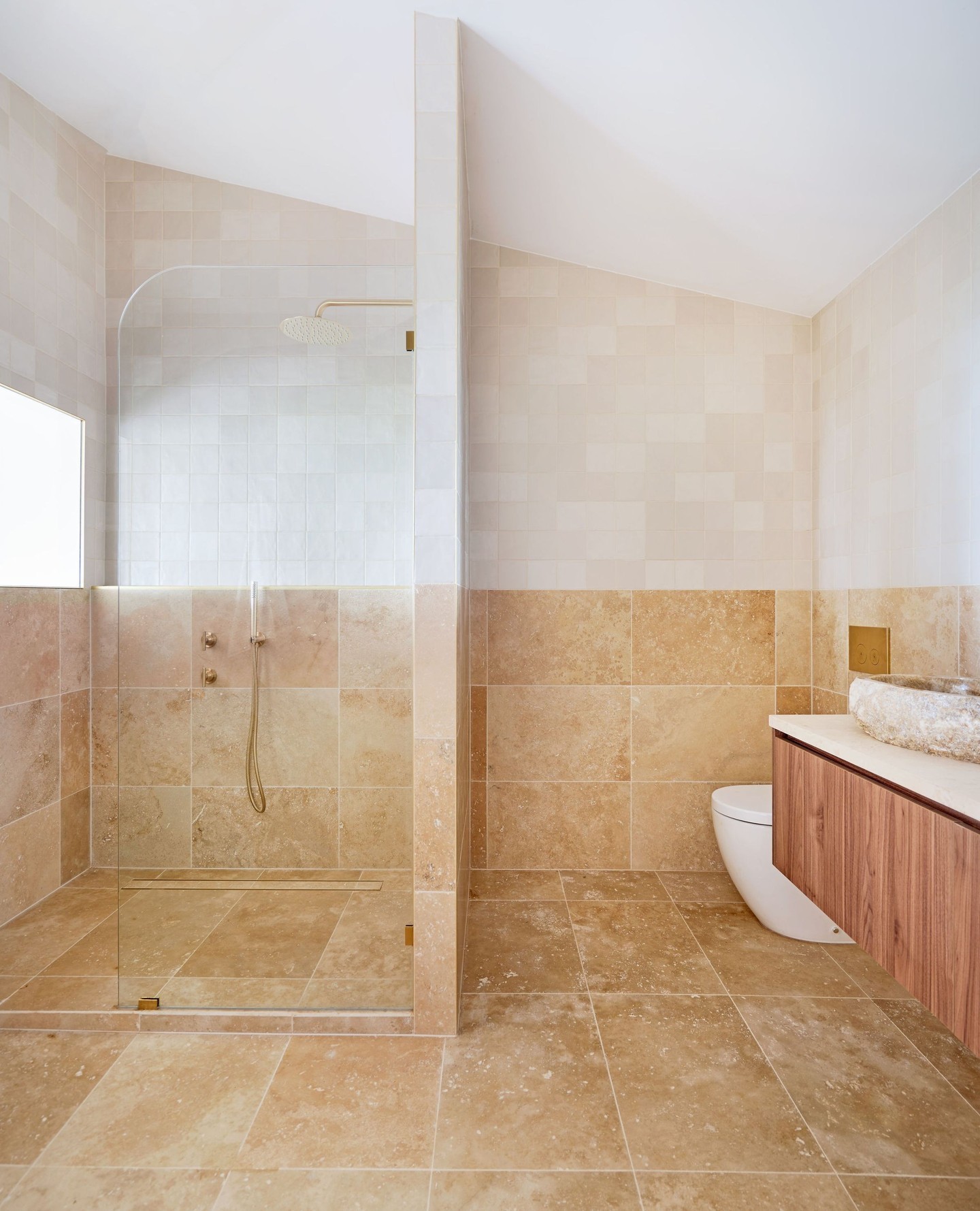 This shower showcases a beautifully tiled half wall that adds texture and depth. The choice of tile complements the rest of the bathroom, creating a cohesive look. 
(@abiinteriors).