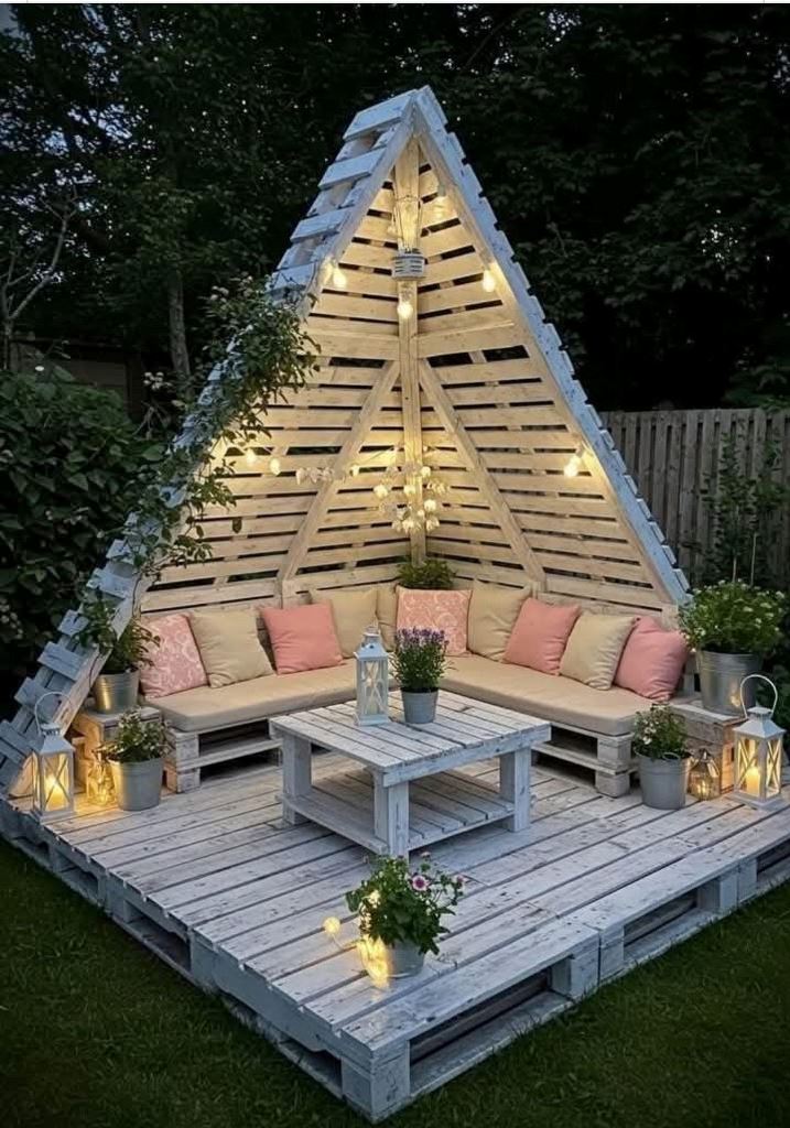 The triangle pergola features lights, blooms and plants and a corner sofa with lots of pillows.