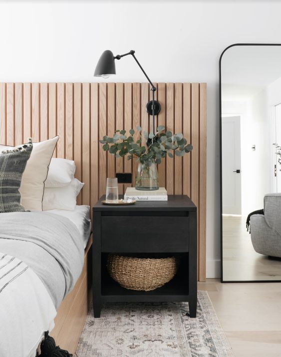 The farmhouse bedroom finished off with a bed, a ribbed headboard, a black nightstand, a boho rug and a black sconce.