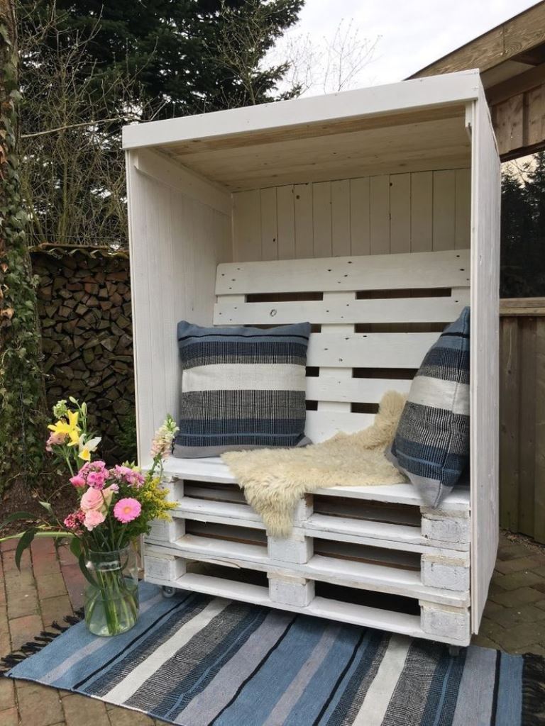 This white arbor is done with tiered pallets that compose a seat, and with large pillows.