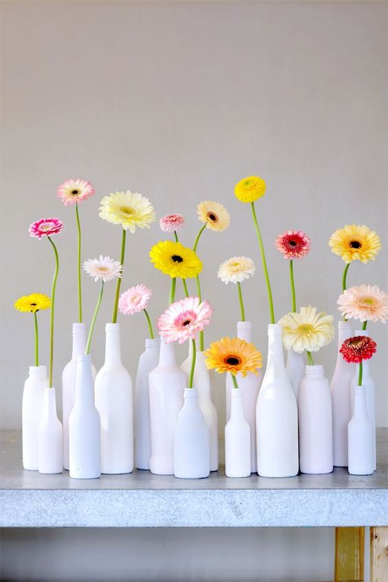 White bottles with colorful gerberas for a modern and bold summer decoration that is easy to compose.