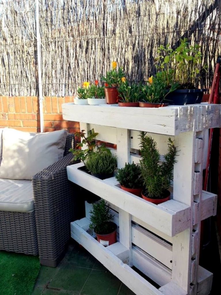 This white pallet is a cool plant stand, and if you add wheels, you will be able to place it and move it where you need.
