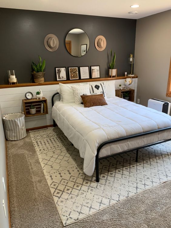 The modern farmhouse bedroom is done with a grey wall, a white planked headboard with decor and crate shelves, a metal bed and layered rugs.