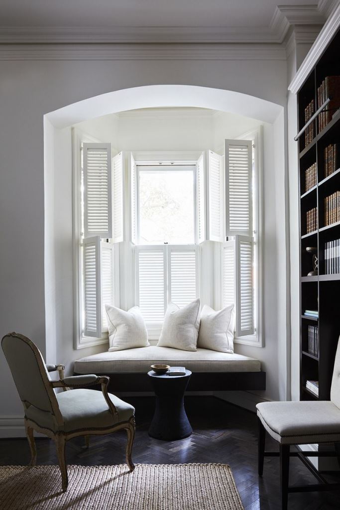 The arched window is styled with shutters that block out the view and keep the space peacefully shady.